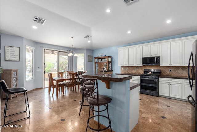 kitchen with decorative backsplash, white cabinets, hanging light fixtures, a breakfast bar, and stainless steel appliances