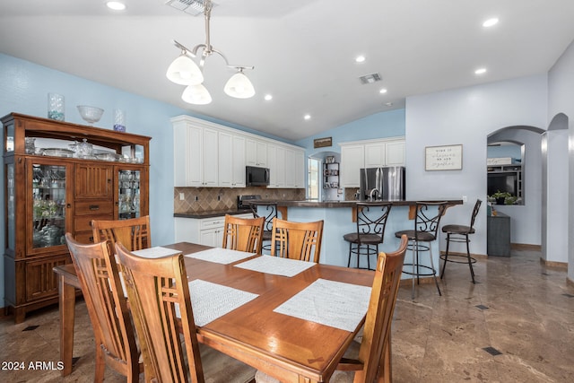 dining area featuring an inviting chandelier and vaulted ceiling