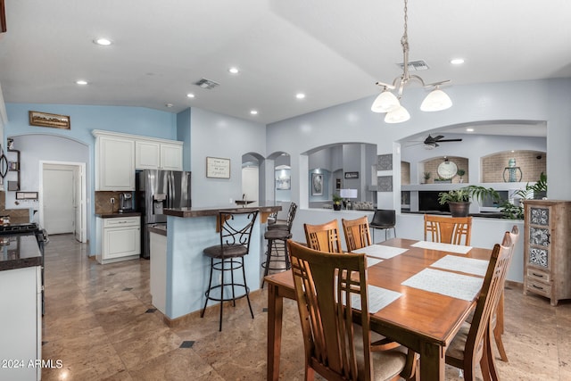 dining area featuring lofted ceiling and ceiling fan with notable chandelier