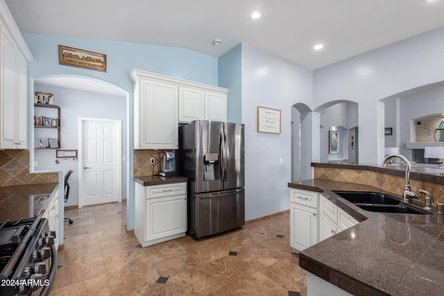 kitchen featuring sink, white cabinets, vaulted ceiling, appliances with stainless steel finishes, and tasteful backsplash