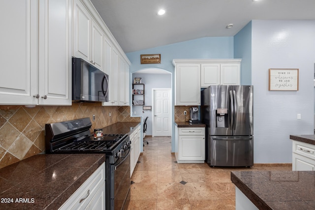 kitchen featuring black gas range, lofted ceiling, stainless steel fridge, white cabinets, and tasteful backsplash