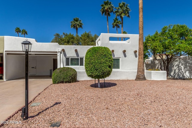 pueblo revival-style home with concrete driveway and stucco siding