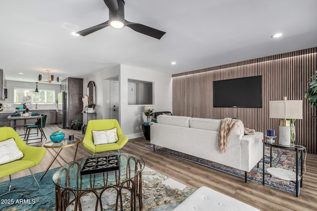 living area with ceiling fan, baseboards, light wood finished floors, recessed lighting, and an accent wall