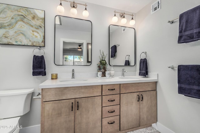 full bath with baseboards, toilet, and double vanity