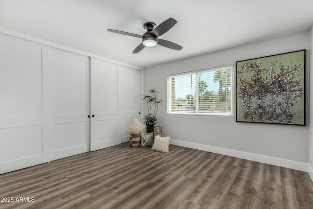 unfurnished bedroom with wood finished floors, a closet, baseboards, and ceiling fan