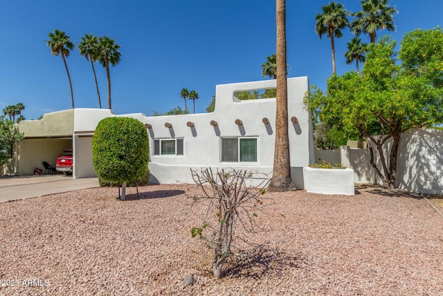 pueblo revival-style home with stucco siding and fence