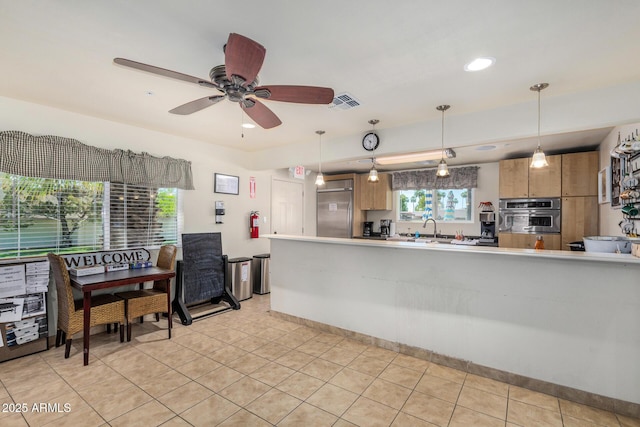 kitchen with stainless steel appliances, a sink, decorative light fixtures, ceiling fan, and light tile patterned floors