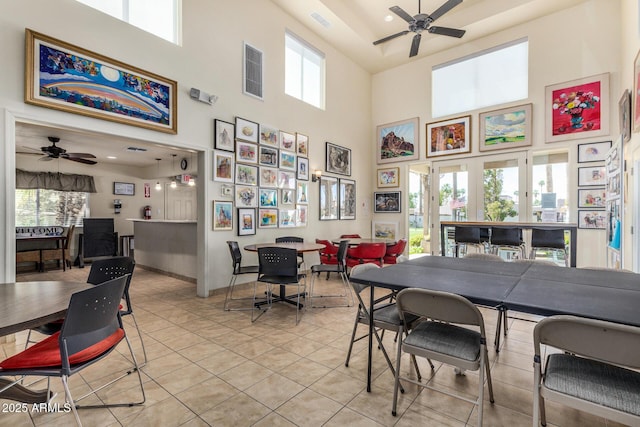 dining space featuring a ceiling fan, a high ceiling, light tile patterned flooring, and baseboards
