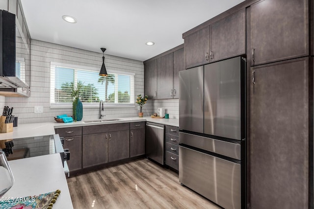 kitchen with appliances with stainless steel finishes, a sink, dark brown cabinets, light countertops, and recessed lighting