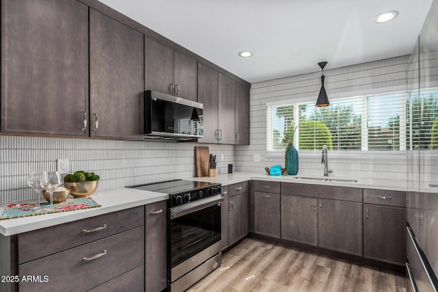 kitchen with appliances with stainless steel finishes, a sink, decorative backsplash, dark brown cabinetry, and recessed lighting
