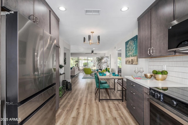 kitchen featuring appliances with stainless steel finishes, dark brown cabinetry, light wood-style flooring, and recessed lighting
