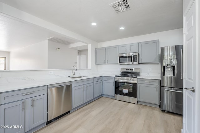 16159 W Maui Ln, Surprise, AZ 85379 - kitchen featuring stainless steel appliances, a sink, gray cabinets, light wood-style floors, and recessed lighting