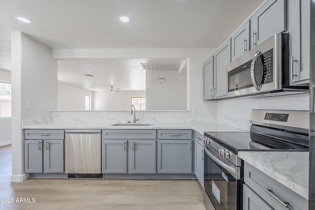 16159 W Maui Ln, Surprise, AZ 85379 - kitchen with stainless steel appliances, gray cabinets, a sink, light wood-type flooring, and recessed lighting