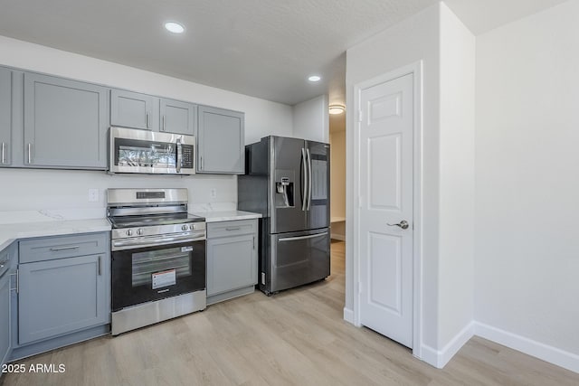 16159 W Maui Ln, Surprise, AZ 85379 - kitchen with appliances with stainless steel finishes, gray cabinets, light wood finished floors, baseboards, and recessed lighting