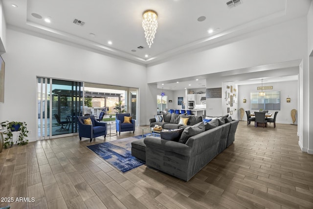 living room featuring a chandelier, a raised ceiling, and a high ceiling