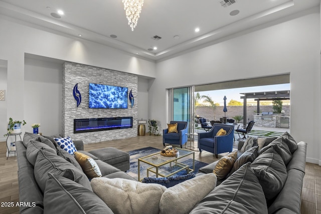 living room featuring a high ceiling, a stone fireplace, and hardwood / wood-style floors