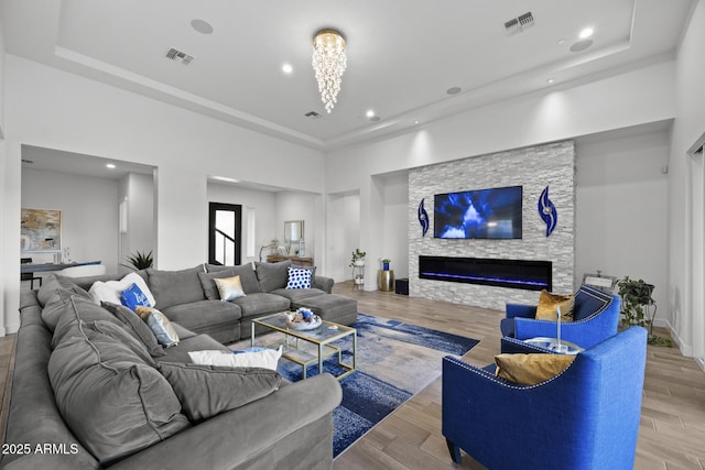 living room with a fireplace, light hardwood / wood-style floors, and a raised ceiling