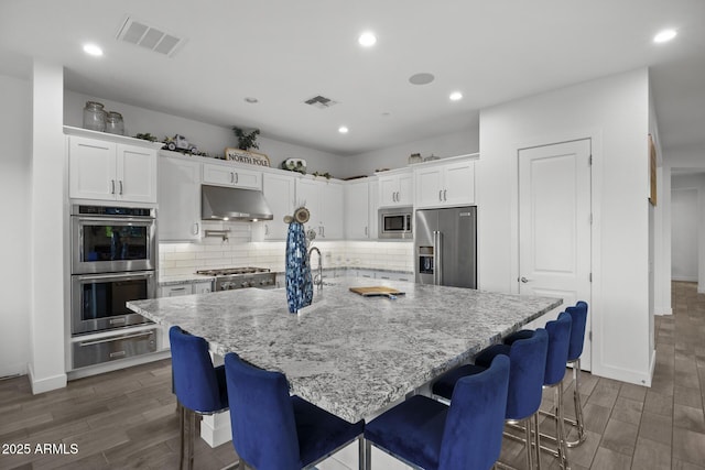 kitchen featuring white cabinetry, a breakfast bar area, stainless steel appliances, and a spacious island