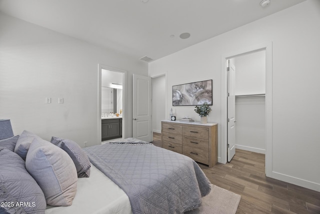 bedroom with dark hardwood / wood-style flooring, a walk in closet, a closet, and ensuite bathroom