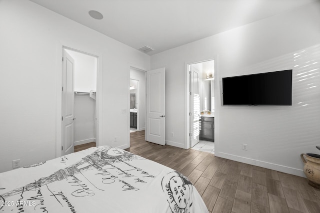 bedroom featuring ensuite bathroom, a walk in closet, and a closet