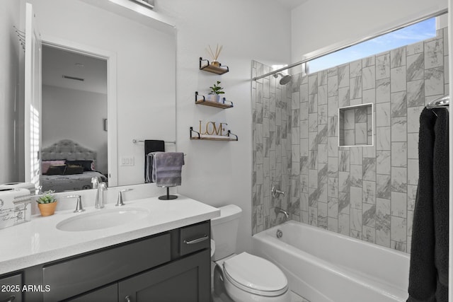 full bathroom featuring tiled shower / bath, vanity, and toilet