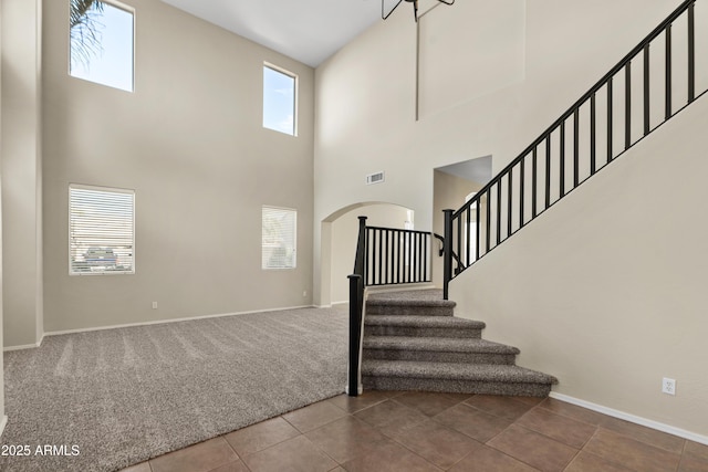 stairs with a towering ceiling and tile patterned floors