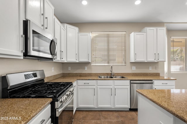 kitchen with sink, light stone counters, white cabinets, and stainless steel appliances