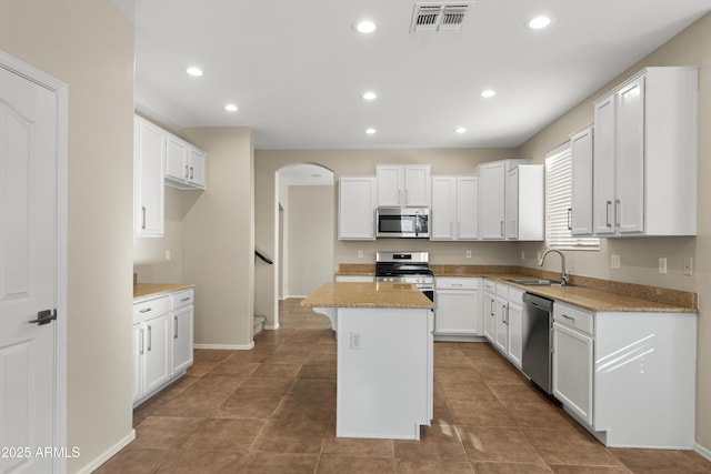 kitchen with white cabinets, a center island, appliances with stainless steel finishes, and sink