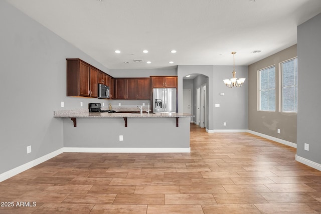 3036 N Acacia Way, Buckeye, AZ 85396 - kitchen featuring stainless steel appliances, a peninsula, arched walkways, a chandelier, and light wood-style floors