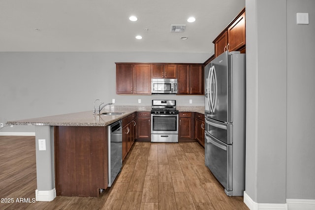 3036 N Acacia Way, Buckeye, AZ 85396 - kitchen featuring stainless steel appliances, light wood-style flooring, light stone countertops, a peninsula, and recessed lighting