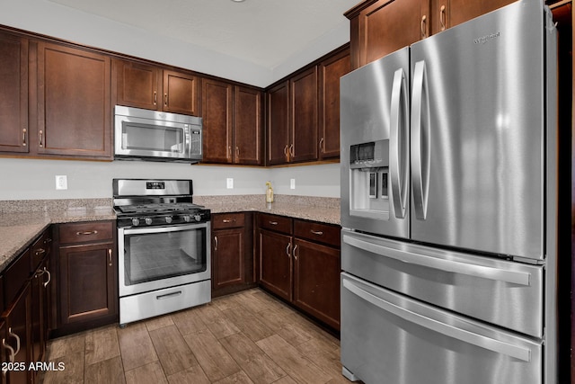 3036 N Acacia Way, Buckeye, AZ 85396 - kitchen featuring appliances with stainless steel finishes, dark brown cabinets, light stone counters, and wood finished floors