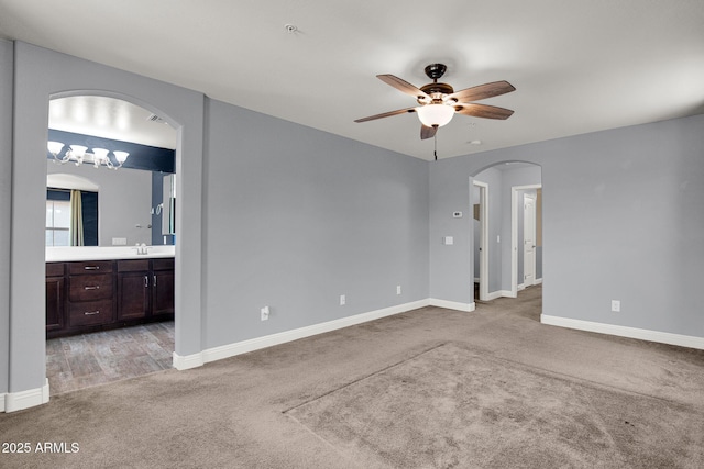 3036 N Acacia Way, Buckeye, AZ 85396 - unfurnished room featuring arched walkways, light carpet, a ceiling fan, and fire sprinkler in ceiling