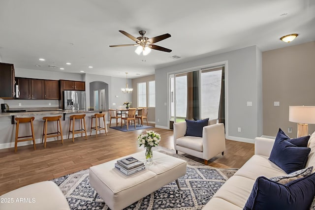 3036 N Acacia Way, Buckeye, AZ 85396 - living area featuring a chandelier, a ceiling fan, light wood finished floors, recessed lighting, and arched walkways