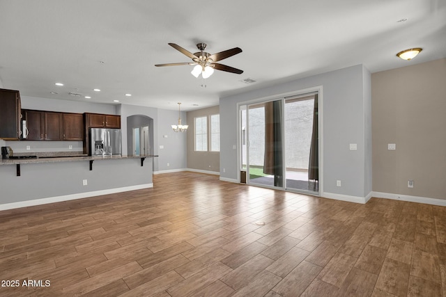3036 N Acacia Way, Buckeye, AZ 85396 - unfurnished living room featuring ceiling fan, a chandelier, light wood-type flooring, recessed lighting, and arched walkways