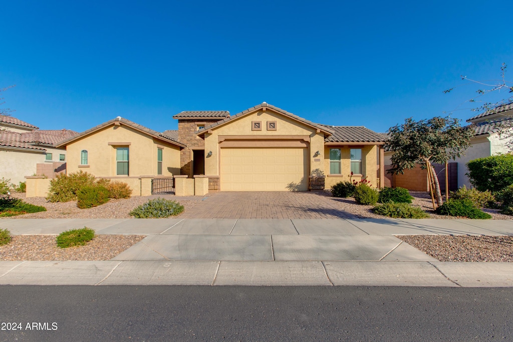 mediterranean / spanish home with stucco siding, an attached garage, driveway, and a tile roof