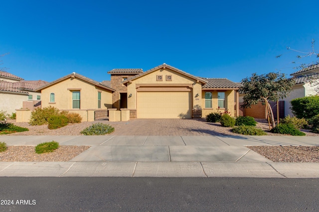 mediterranean / spanish home with stucco siding, an attached garage, driveway, and a tile roof