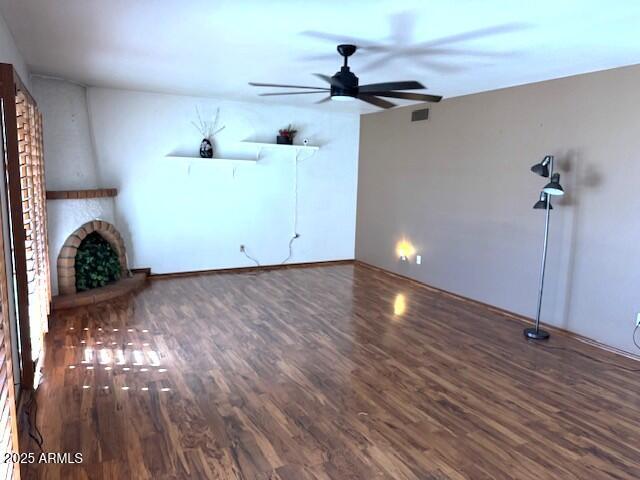 unfurnished living room featuring dark hardwood / wood-style floors, a brick fireplace, and ceiling fan