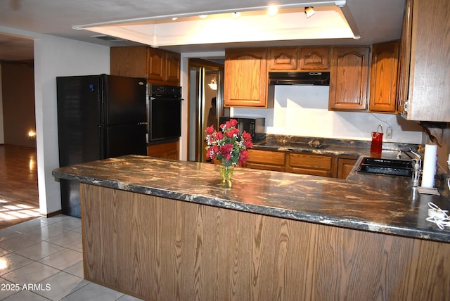 kitchen with a raised ceiling, kitchen peninsula, sink, and black appliances