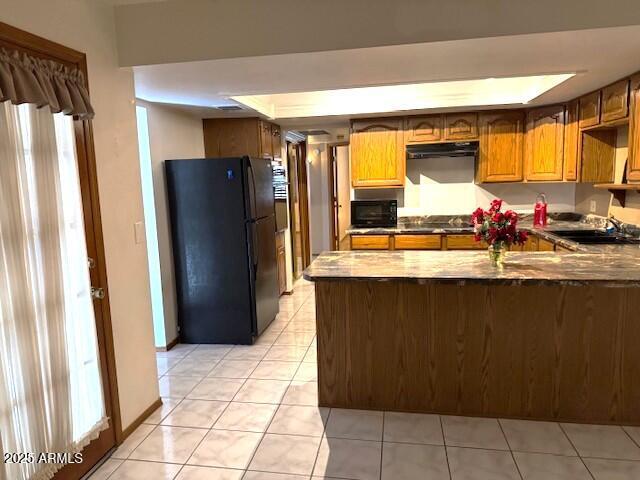 kitchen featuring kitchen peninsula, sink, light tile patterned floors, and black appliances