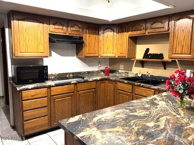 kitchen with dark stone countertops, sink, light tile patterned floors, and gas cooktop