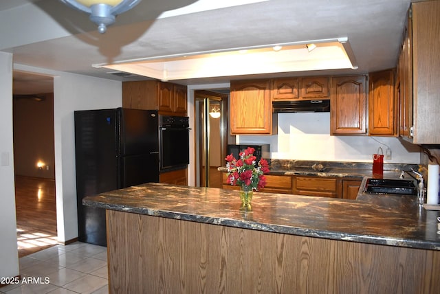 kitchen with kitchen peninsula, sink, black appliances, dark stone countertops, and light tile patterned flooring