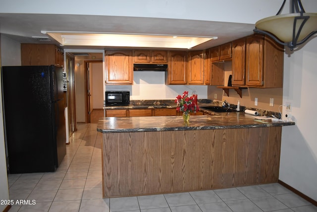 kitchen featuring black appliances, sink, dark stone countertops, light tile patterned flooring, and kitchen peninsula