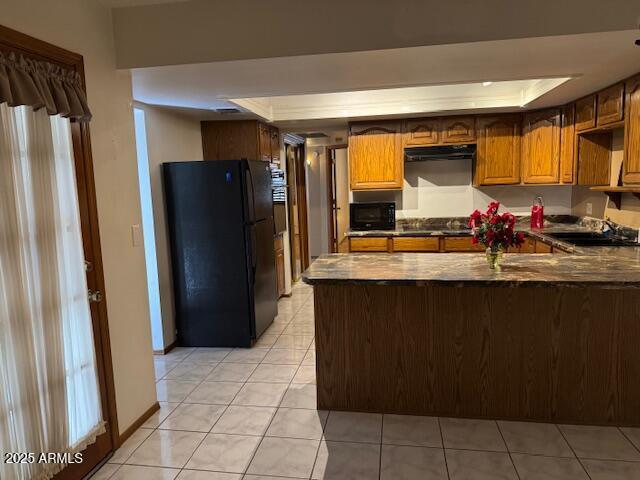 kitchen with kitchen peninsula, light tile patterned floors, sink, and black appliances