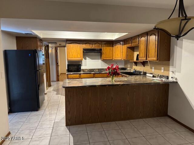 kitchen featuring pendant lighting, black appliances, sink, light tile patterned floors, and kitchen peninsula