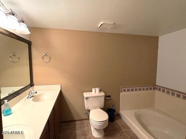 bathroom with toilet, a washtub, vanity, and tile patterned flooring