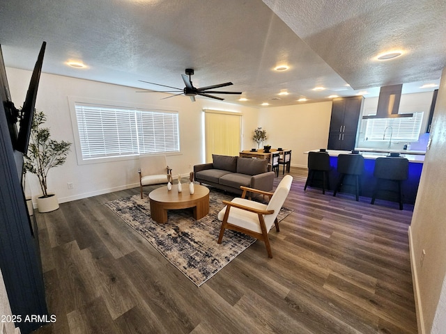 living area featuring ceiling fan, baseboards, dark wood finished floors, and a textured ceiling