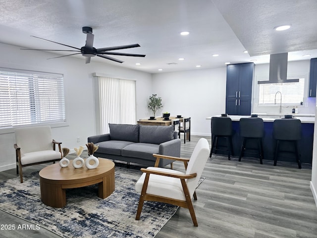 living room with light wood finished floors, baseboards, a textured ceiling, and recessed lighting