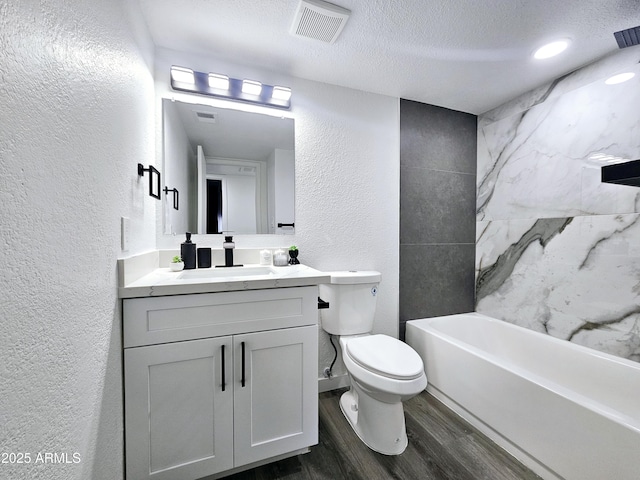 full bathroom with visible vents, a textured wall, wood finished floors, a textured ceiling, and vanity