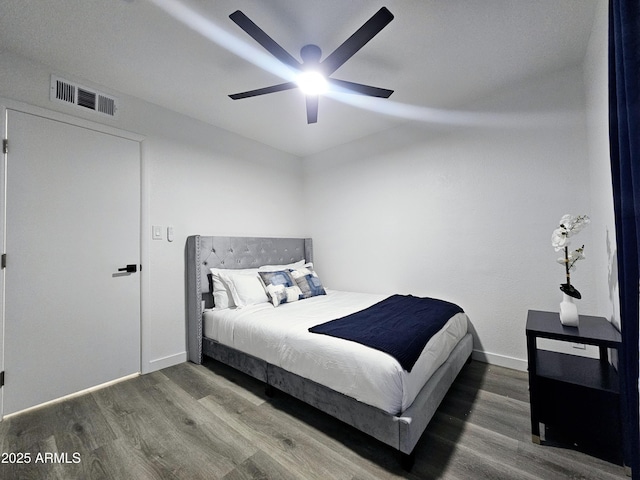 bedroom featuring a ceiling fan, wood finished floors, visible vents, and baseboards