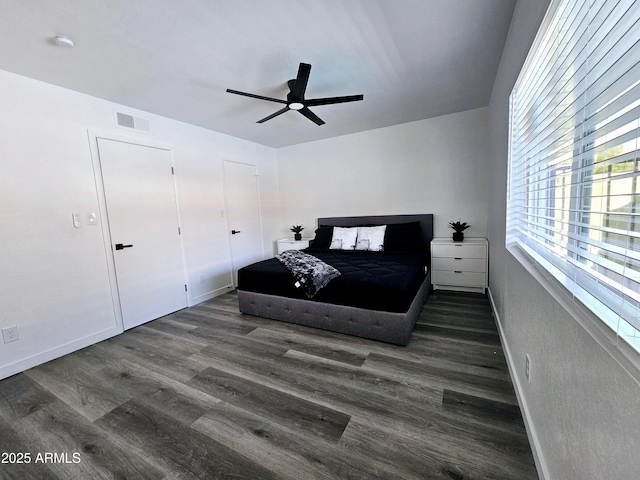 bedroom with dark wood-style floors, visible vents, baseboards, and a ceiling fan